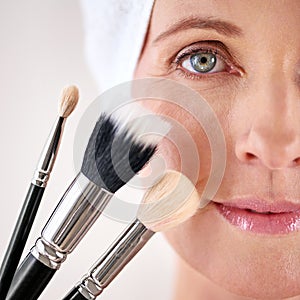 Beauty time. Closeup studio portrait of a mature woman posing with a set of makeup brushes.