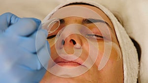 Beauty treatment. Beautician applies patches to remove puffiness under eyes, lighten, smooth and tighten soft skin