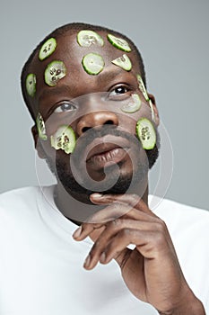 Beauty Treatment. Cucumber Mask As Skin Care. African Male Model Doing Facecare Routine. photo