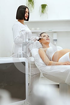 Beauty Treatment. Pregnant Woman Getting Therapy On Facial Skin