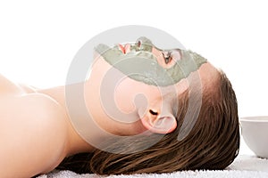 Beauty treatment in spa salon. Woman with facial clay mask.