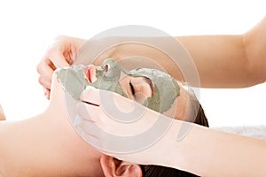 Beauty treatment in spa salon. Woman with facial clay mask.