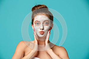 Beauty treatment - woman applying clay face mask