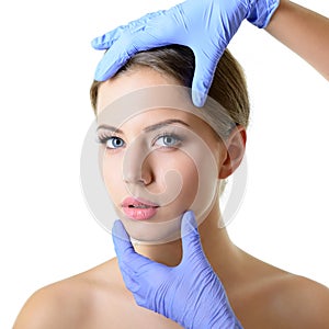 Beauty treatment for young beautiful female face, doctor`s hand in gloves touch face of beautiful young woman isolated on white.