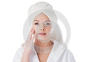 Beauty treatments after the bath. Portrait of a young beautiful woman in a Terry robe and with a towel on her head.