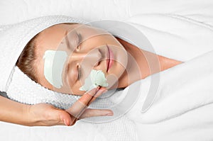 Beauty Treatments. Woman applying facial mask at spa