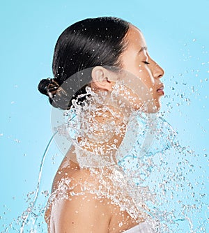 Beauty, water and face of woman on blue background for wellness, healthy skin and cleaning in studio. Skincare, shower