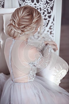 Beauty wedding hairstyle. Bride. Blond girl with curly hair styling. Back view of elegant lady in bridal dress.