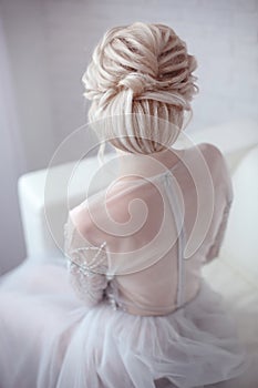 Beauty wedding hairstyle. Bride. Blond girl with curly hair styling. Back view of elegant lady in bridal dress.