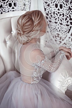 Beauty wedding hairstyle. Bride. Blond girl with curly hair styling. Back view of elegant lady in bridal dress.
