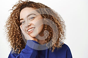 Beauty and wellbeing. Close up portrait of beautiful curly girl with perfect, healthy face, touching her skin and