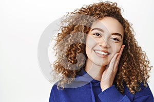 Beauty and wellbeing. Close up portrait of beautiful curly girl with perfect, healthy face, touching her skin and