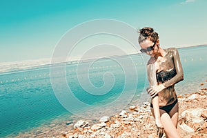 Beauty and Wellness. Spa Outdoor. Woman smearing mud mask on body, beach Dead Sea. Recreation tourism, healthy lifestyle, body car