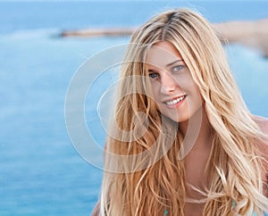 Beauty, wellness and summer portrait. Beautiful young woman with long blond hair, happy blonde smiling, blue sea on