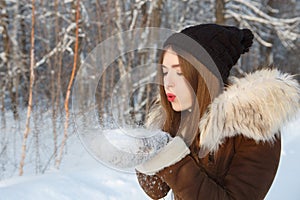Beauty Winter Girl Blowing Snow in frosty winter Park.