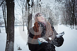 Beauty Winter Girl Blowing Snow in frosty winter Park