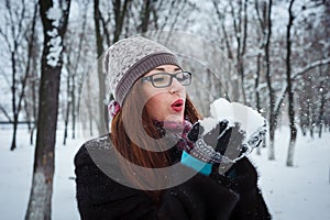 Beauty Winter Girl Blowing Snow in frosty winter Park