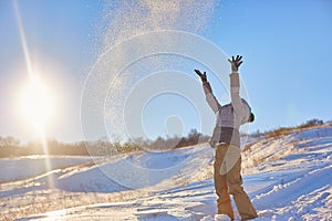 Beauty Winter Girl Blowing Snow in frosty winter Park. Outdoors. Flying Snowflakes. Sunny day. Backlit. Beauty young