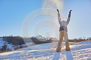 Beauty Winter Girl Blowing Snow in frosty winter Park. Outdoors. Flying Snowflakes. Sunny day. Backlit. Beauty young woman Having