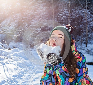 Beauty Winter Girl Blowing Snow in frosty winter Park. Outdoors. Flying Snowflakes. Sunny day. Backlit. Joyful Beauty