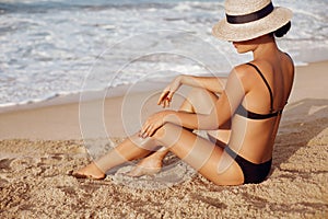 Beauty Woman applying sun cream lotion on legs. Skin cream.  A Female  smear  sunscreen on beautiful legs on beach.