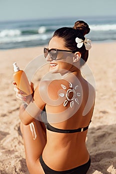 Beauty Woman Applying Sun Cream  on Tanned  Shoulder In Form Of The Sun. Sun Protection.Sun Cream