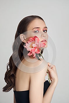 Beauty Woman with big pink flowers, studio portrait. Perfect body, pink professional makeup on a woman face. Curly hair