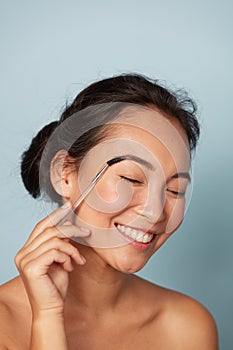 Beauty. Woman brushing eyebrows with makeup brush portrait