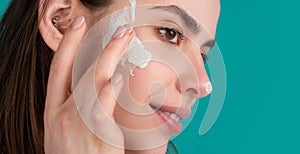 Beauty woman with clean healthy skin, natural make up, spa concept. Beautiful girl applying face cream, closeup.