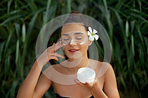 Beauty Woman Concept. Skin care.  Portrait of female model  holding and applying cosmetic moisturizing cream