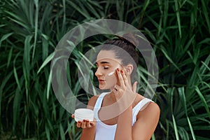 Beauty Woman Concept. Skin care.  Portrait of female model  holding and applying cosmetic moisturizing cream