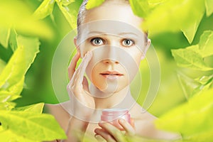 Beauty woman with cream and natural skin care in green