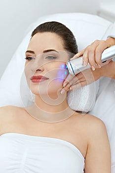 Beauty. Woman Doing Blue Light Facial Treatment On Face Skin