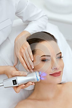 Beauty. Woman Doing Blue Light Facial Treatment On Face Skin