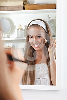 Beauty woman doing her makeup in the mirror
