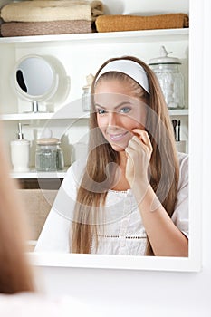 Beauty woman examining her face in the mirror