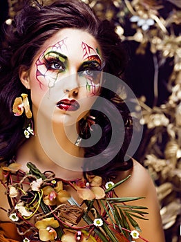 Beauty woman with face art and jewelry from flowers orchids close up, creative makeup floral pattern background