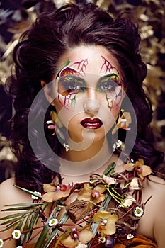 Beauty woman with face art and jewelry from flowers orchids close up, creative makeup floral pattern background