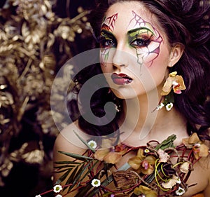 Beauty woman with face art and jewelry from flowers orchids close up, creative makeup floral pattern background