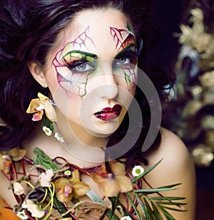 Beauty woman with face art and jewelry from flowers orchids close up, creative pattern makeup floral pattern background