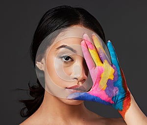 Beauty, woman and face, paint on palm with art, colorful aesthetic and makeup with color in portrait on studio