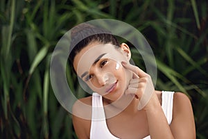 Beauty Woman face Portrait. Beautiful Spa model Girl with Perfect Fresh Clean Skin apply moisturizing cream. Skin care.