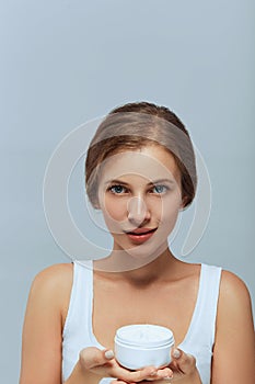 Beauty Woman Face Skin Care. Portrait Of Attractive Young Female Applying Cream  And Holding Bottle.