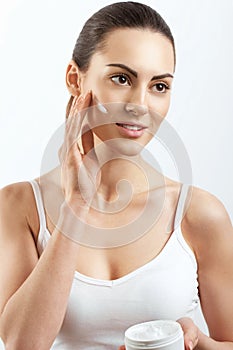 Beauty Woman Face Skin Care.  Woman Face Skin Care. Portrait Of Attractive Young Female Applying Cream  And Holding Bottle.