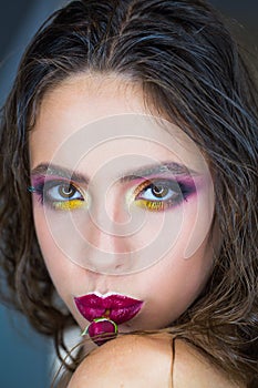 Beauty woman with glamour look, makeup and flower in purple lips. Woman with red rose in mouth, womens day. Fashion