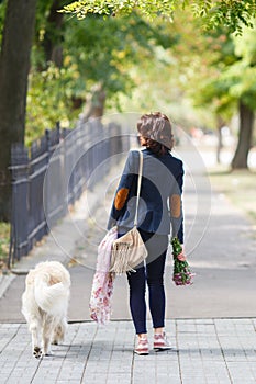 Beauty woman with her dog playing outdoors. Woman walking Labrador Retriever in park. Girl with dog on the street