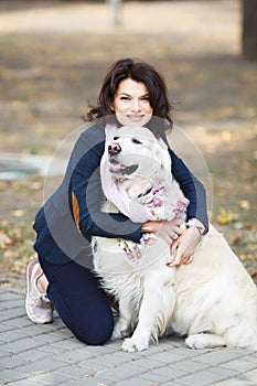 Beauty woman with her dog playing outdoors. Woman walking Labrador Retriever in park. Girl with dog on the street