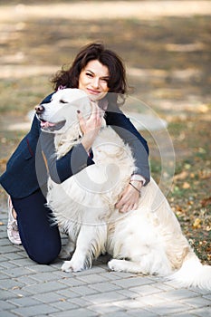 Beauty woman with her dog playing outdoors. Woman walking Labrador Retriever in park. Girl with dog on the street