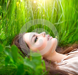 Beauty woman lying on the field in green grass