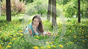 Beauty Woman in the Meadow. Beautiful Young Girl Outdoors. Enjoy Nature. Healthy Smiling Girl lying on Green Grass with